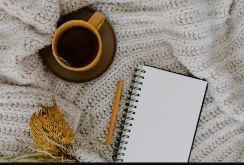 Ambiance cosy avec plaid, tasse de thé et carnet, illustrant le lien entre cycle menstruel et désir