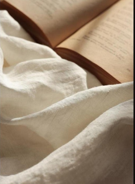 Livre ouvert et lumière douce sur du lin crème, ambiance apaisante pour parler du toucher en douceur