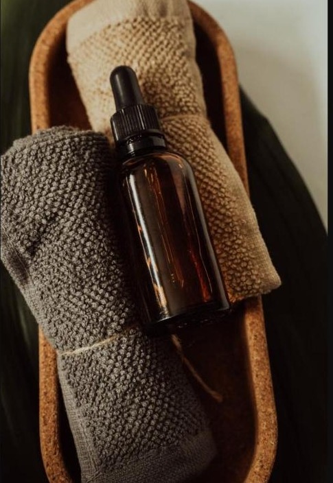 Flacon d'huile de massage entouré de serviettes douces, pour illustrer des exercices simples de reconnexion à son corps
