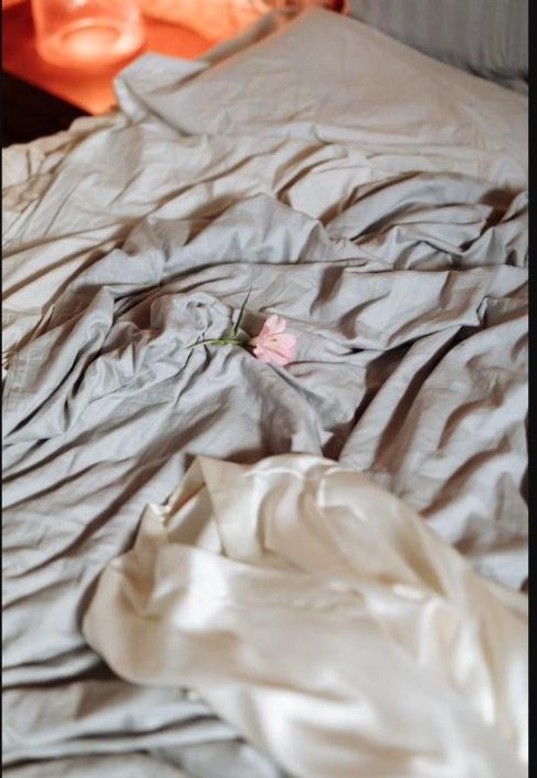 Draps froissés et satin doux avec une fleur, ambiance intime et chaleureuse pour le plaisir seule ou à deux