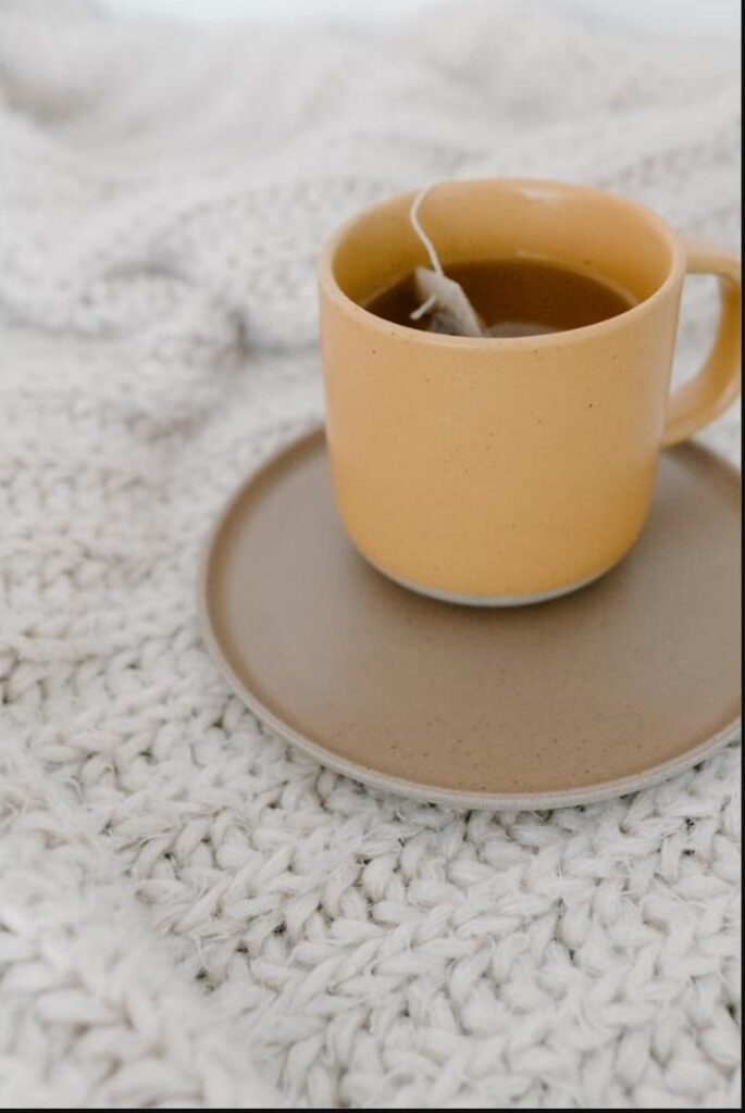 Tasse de tisane chaude sur plaid douillet, moment de réconfort pour les jeunes mamans en post-partum