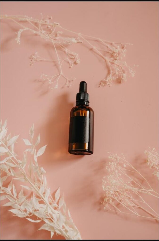 Flacon de lubrifiant intime posé sur fond rose avec branches séchées