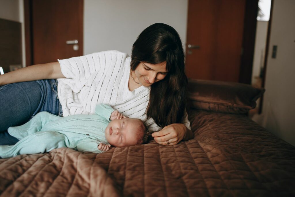 Mère allongée tendrement auprès de son bébé endormi - intimité après l'accouchement