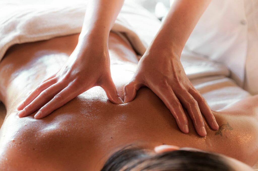 Mains effectuant un massage relaxant dans une lumière douce - massage sensuel